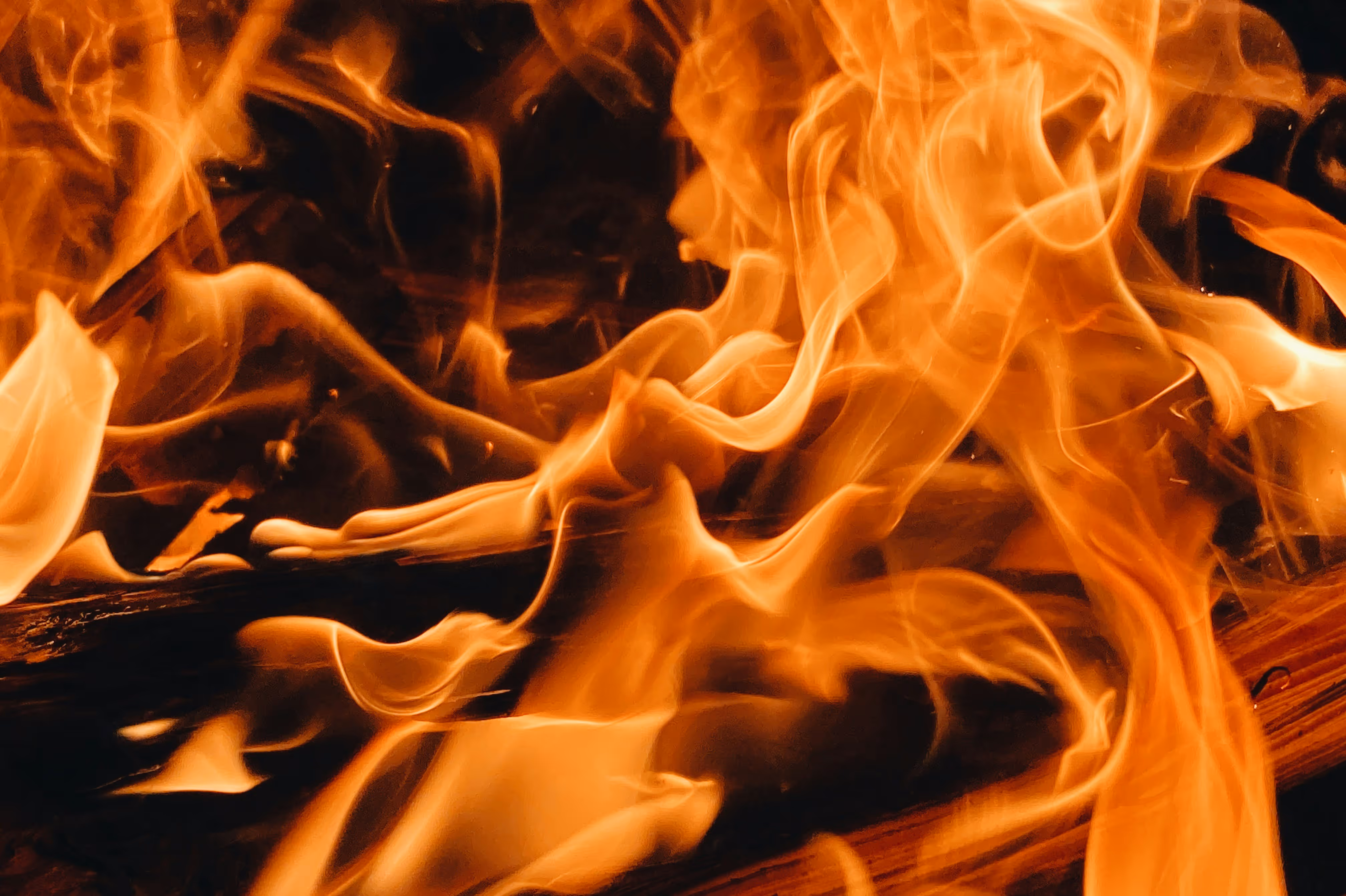 Close-up of bright orange flames burning wood in a fire.