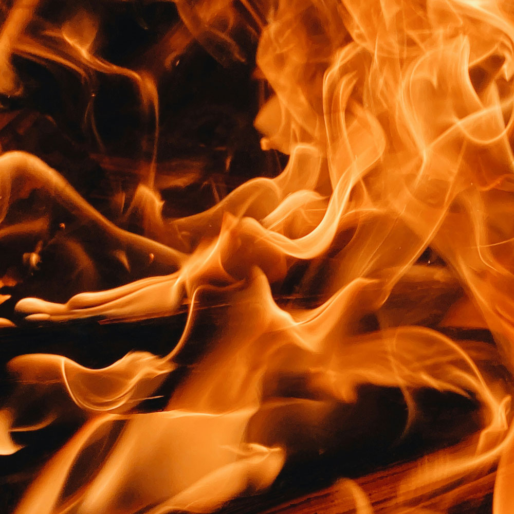 Close-up of bright orange flames with swirling patterns against a dark background.