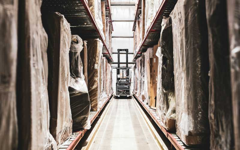Forklift in warehouse with pallets and pallet racking holding freight in storage.