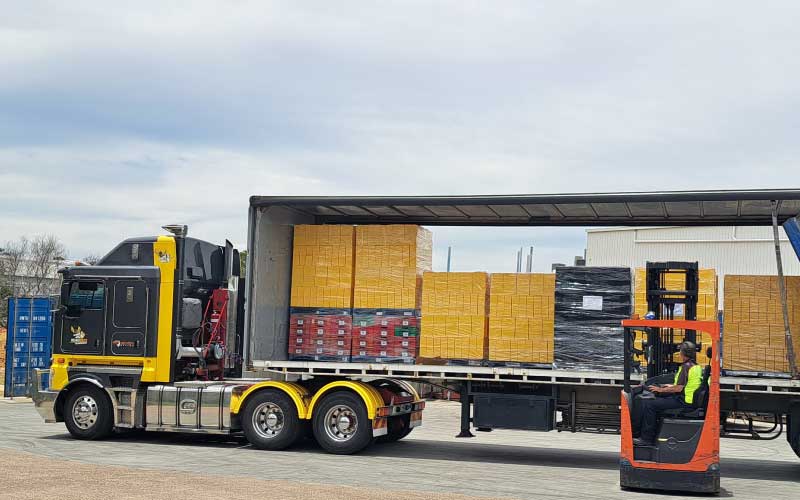 RoadBees Transport Kenworth truck loading freight onto trailer with forklift.