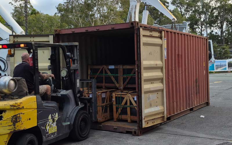 A RoadBees Transport forklift unloads non-dimensional stone crates from a container at the Stapylton Distribution Center