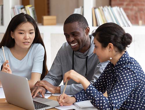 Three young people smiling and looking at a laptop
