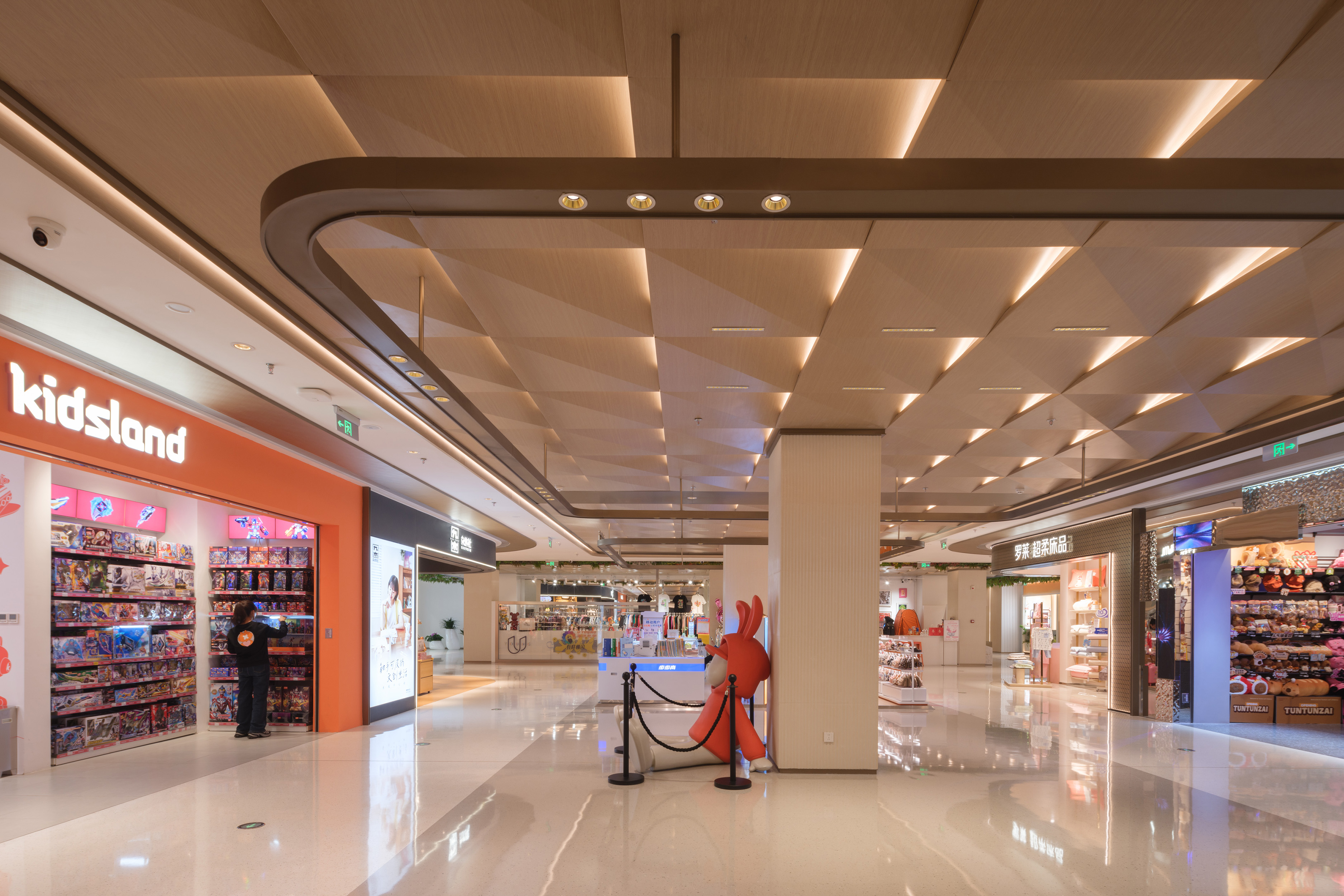 现代购物中心内，人们在明亮的走廊中行走，天花板装饰有圆环形灯光，商店包括Calvin Jeans和DISSONA。