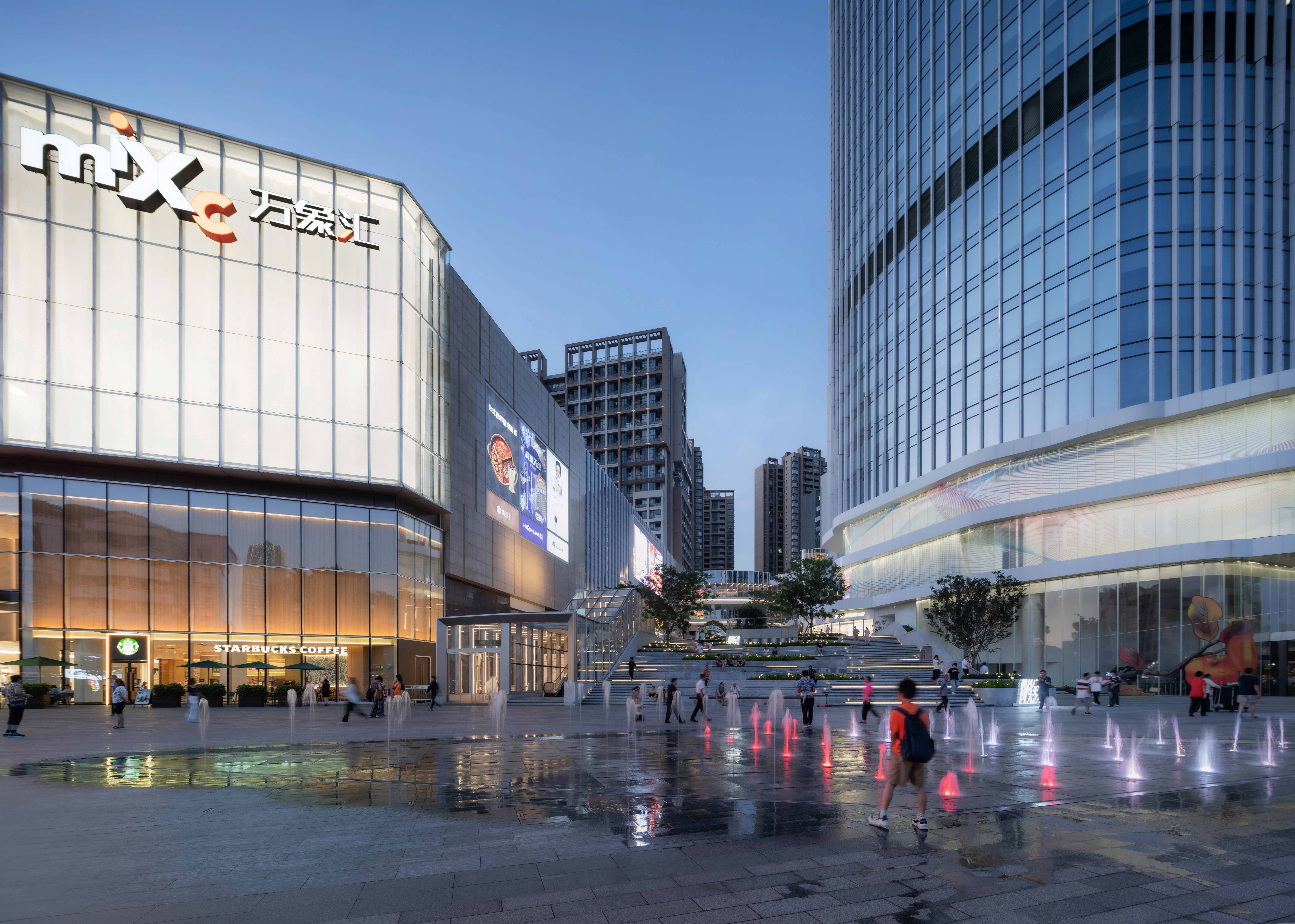 现代购物中心内，人们在明亮的走廊中行走，天花板装饰有圆环形灯光，商店包括Calvin Jeans和DISSONA。