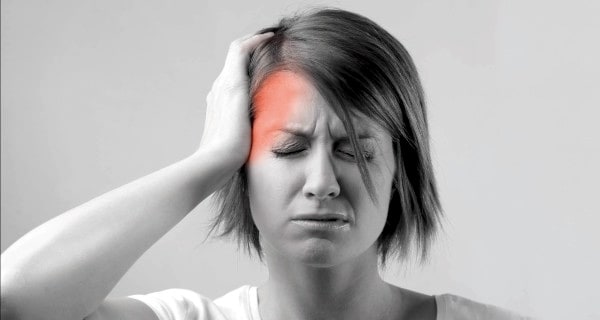 Woman with eyes closed, holding her head; forehead highlighted red to indicate pain.