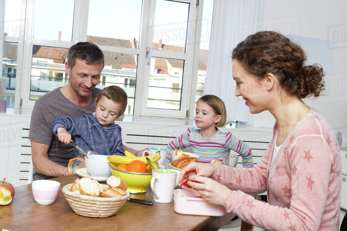 Family of four having breakfast together at a kitchen tableазаара