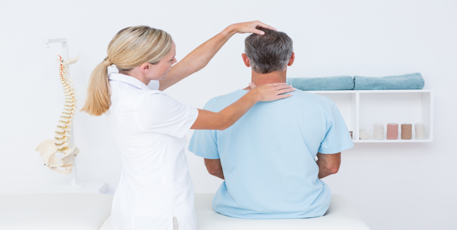 Healthcare professional examining a seated man's neck and shoulder posture from behind.
