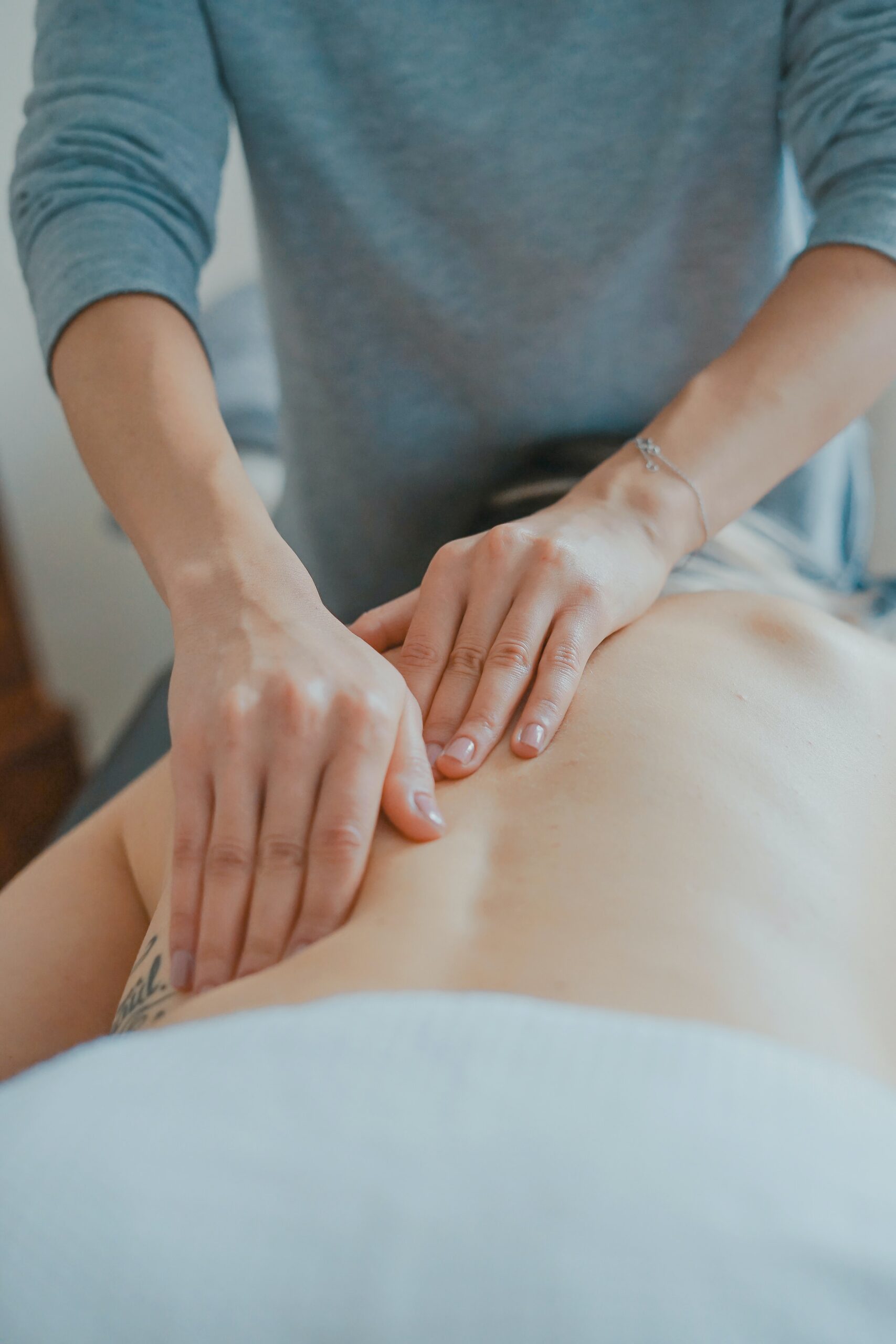 Practitioner pressing both hands on a person’s back during a hands-on session