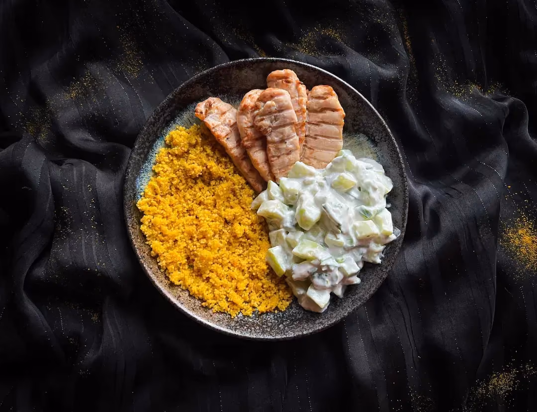 Un petit saladier de couleur bleu accueille les aiguillettes de poulet, la semoule et la salade de concombre.
