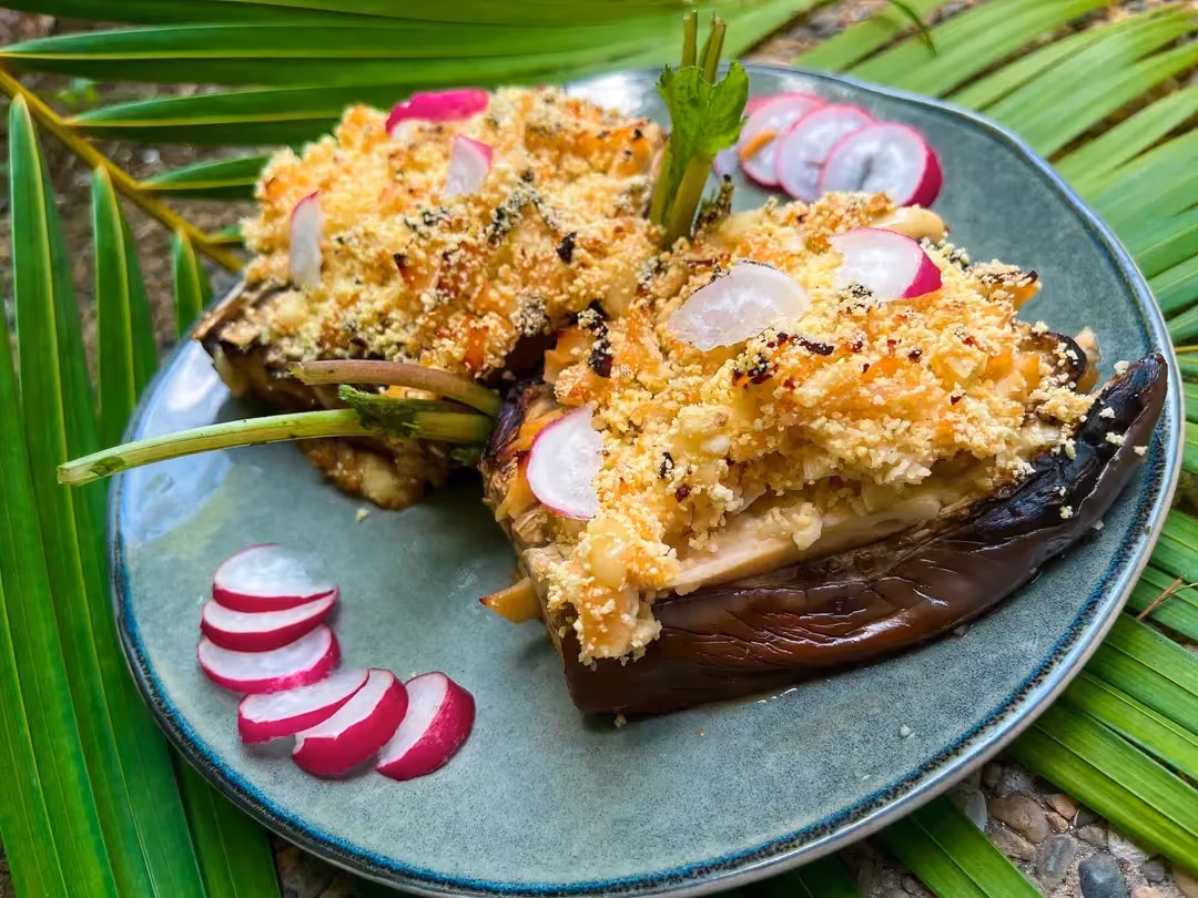 Set on foliage is a beautiful green plate with two large portions of eggplant gratin with turkey ham and cheese.