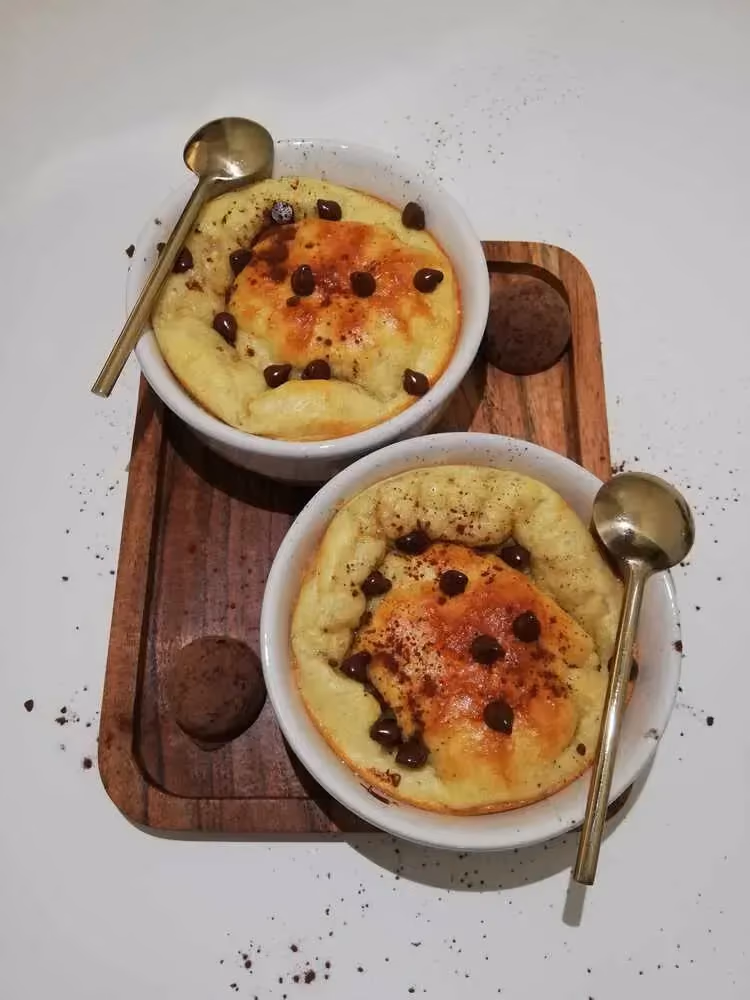 Sur un petit plateau en bois, se trouve deux ramequins individuels avec le gâteau banane. Quelques pépites de chocolat servent de topping.