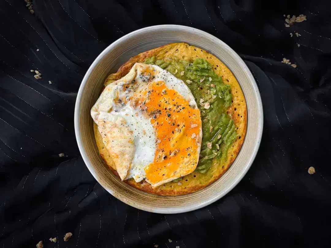 The Big Pancake recipe with pumpkin, avocado, and egg is presented in a small beige stoneware bowl.