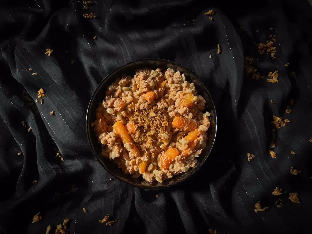 The recipe for wheat with tuna, carrots, and tomato ricotta sauce is presented in a small blue bowl.