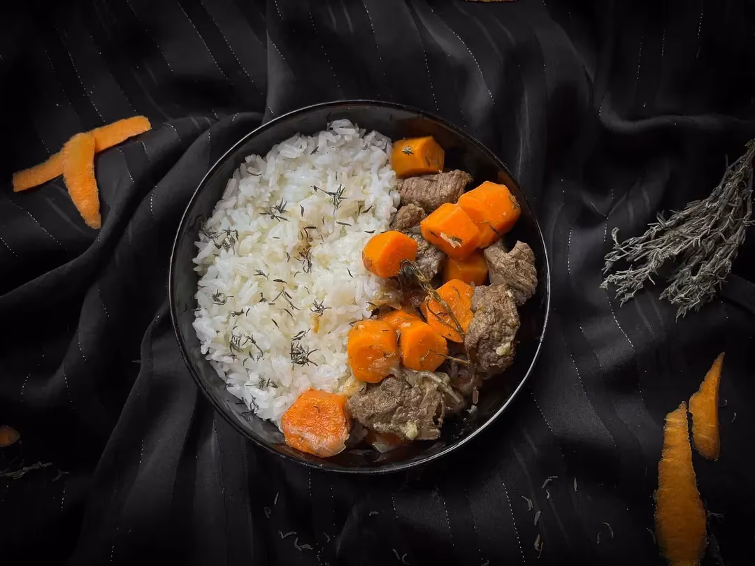 Le boeuf carotte est présenté dans un petit saladier. On retrouve d'un côté du riz blanc et de l'autre des morceaux de boeuf et des carottes.