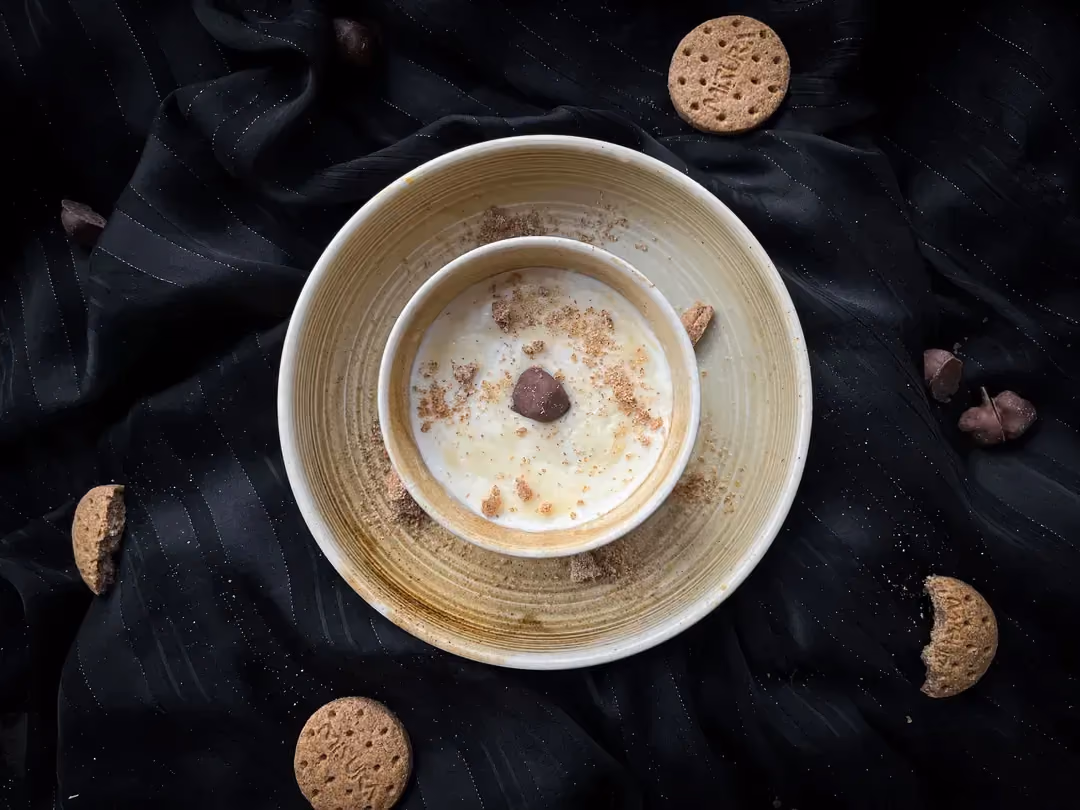 Un petit bol en grès est déposé dans un bol plus grand. Il contient le bol protéiné, biscuit er chocolat blanc. Trois biscuits sont autour des bols.