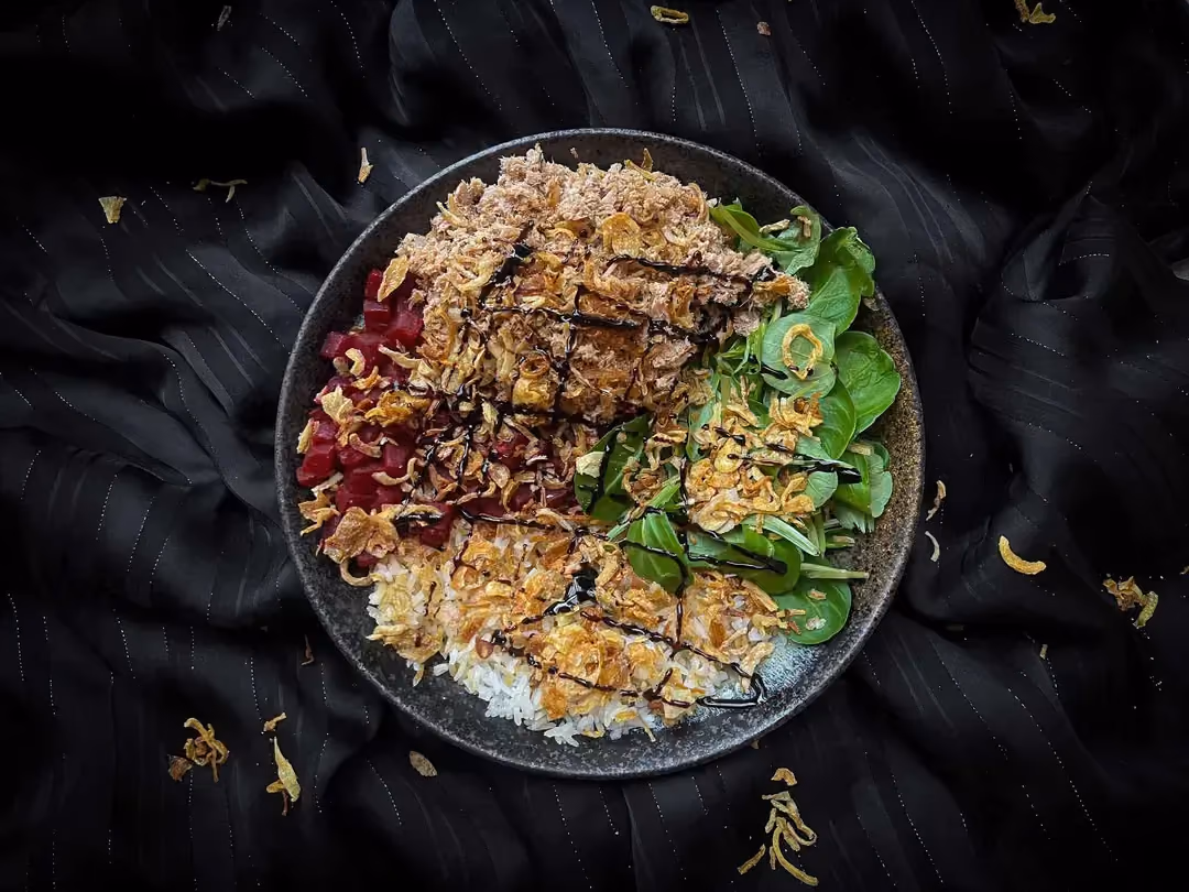 A small blue bowl holds the tuna, rice, beet, and fried onion bowl recipe.