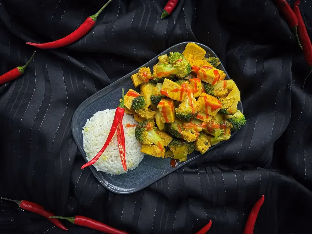 Dans un bol en grès de couleur marron, on retrouve le bol épicé avec le riz, le tofu et les brocolis.