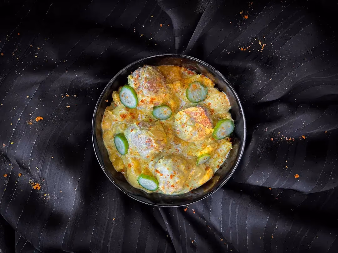 Les boulettes de boeufs baignent dans du lait de coco avec de la mangue coupée en rondelles fines.