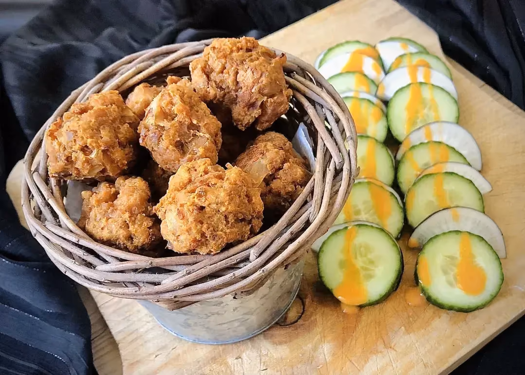 Dans un gros bol, les boulettes de tofu sont dorées par la cuisson. De fines tranches de concombres sont disposées à côté.