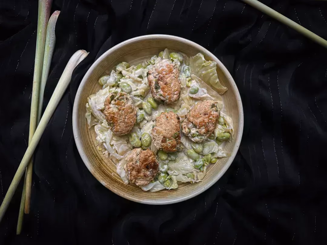 Cinq boulettes de poulet à la citronnelle, coco, edamame et chou vert sont présentent dans un petit saladier en grès de couleur beige.