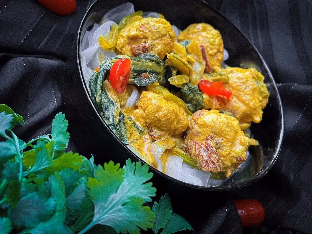 Dans un saladier se trouve cinq belles boulettes de poulet, du pak choi émincé grossièrement, des tomates séchées et des tranches fines de tomate.