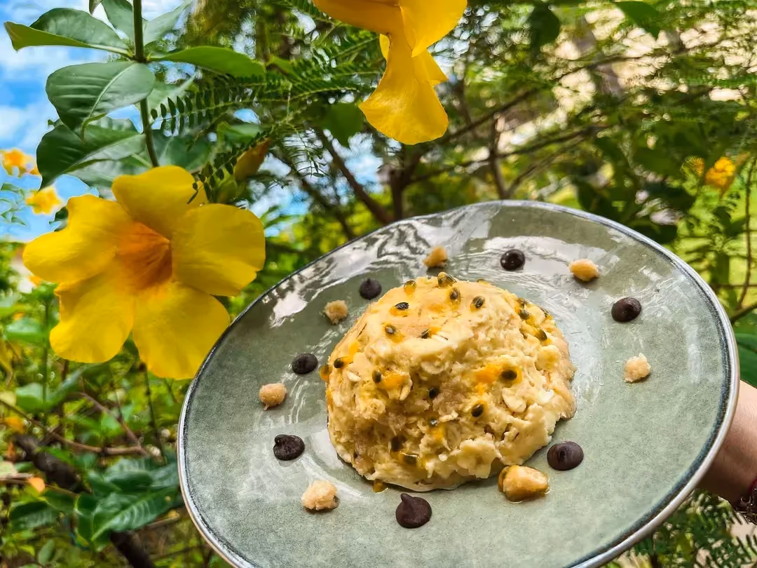 In a natural, floral setting, a blue-gray stoneware plate holds the coconut and barley flake bowl cake.