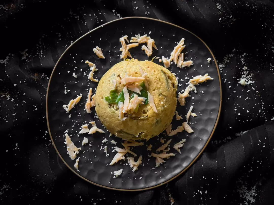 Démoulé, le bowl cake aux haricots verts, jambon et parmesan est présenté dans un petit saladier de couleur bleu alvéolé.