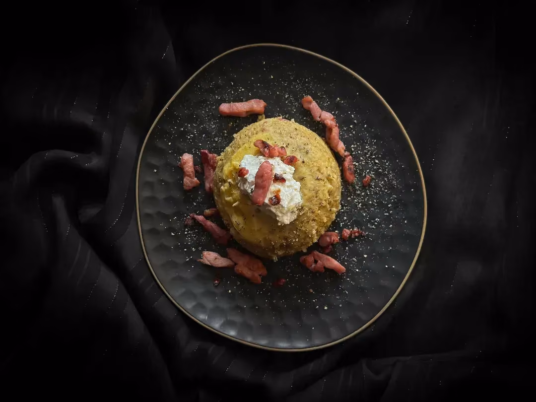 Le bowl cake aux lardons est présenté dans un petit saladier de couleur bleu alvéolé. Du fromage de chèvre sert de topping au bowl cake.