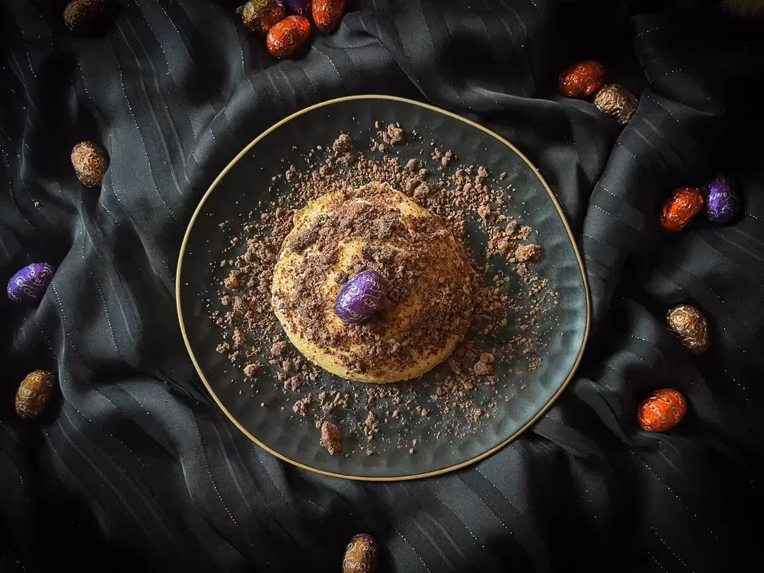 Le Bowl cake de Pâques est présenté dans un petit saladier de couleur bleu alvéolé. De petits oeufs de Pâques sont tout autour du plat.