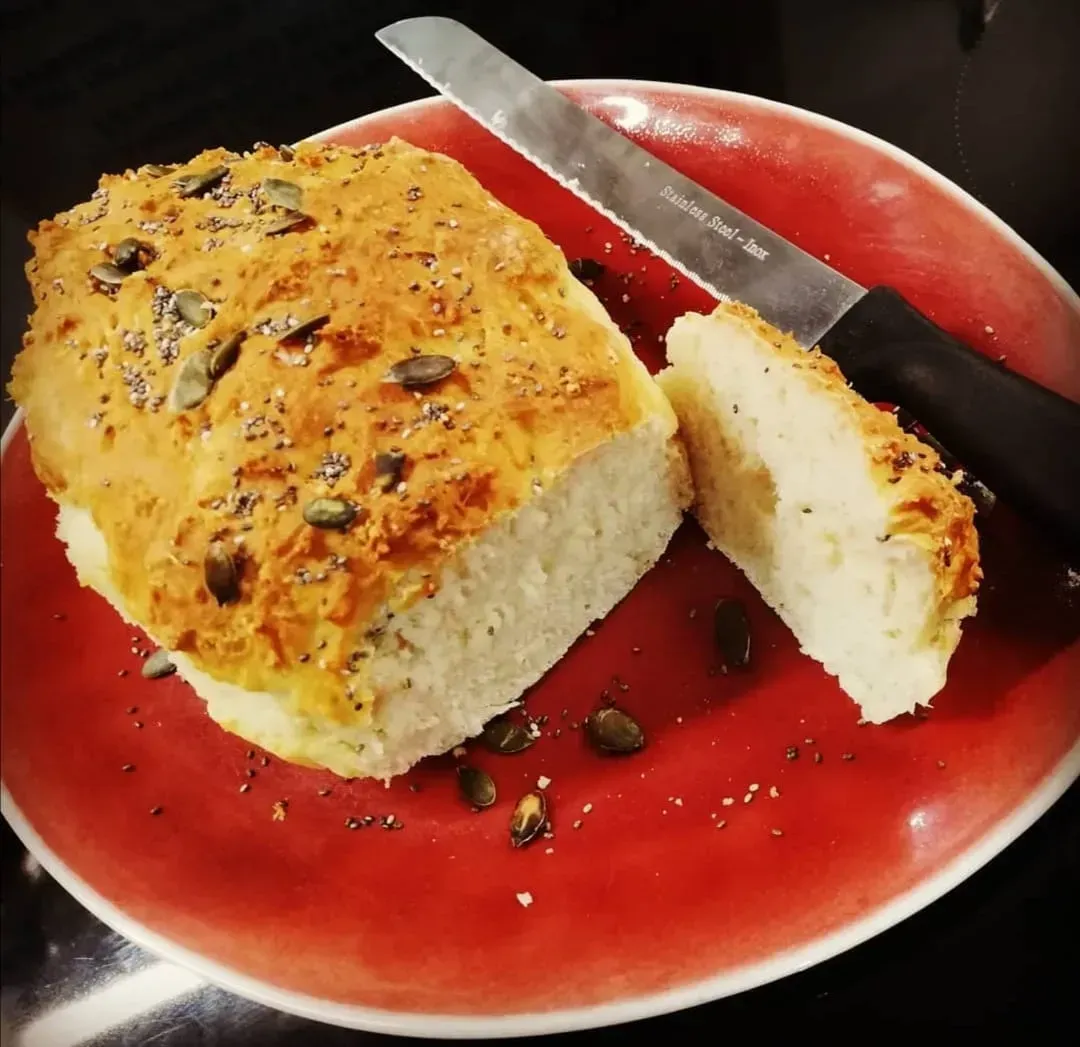 On a red plate is the brioche. One slice has been cut with a bread knife placed beside it.