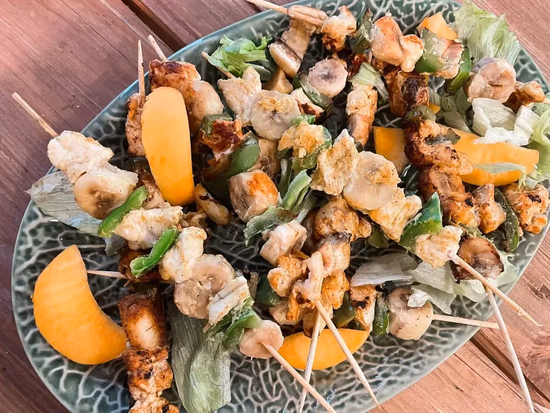 Sur un plat ovale sont disposées les brochettes. Quelques tranches de mangue décorent la recette. Effet visuel garantie !