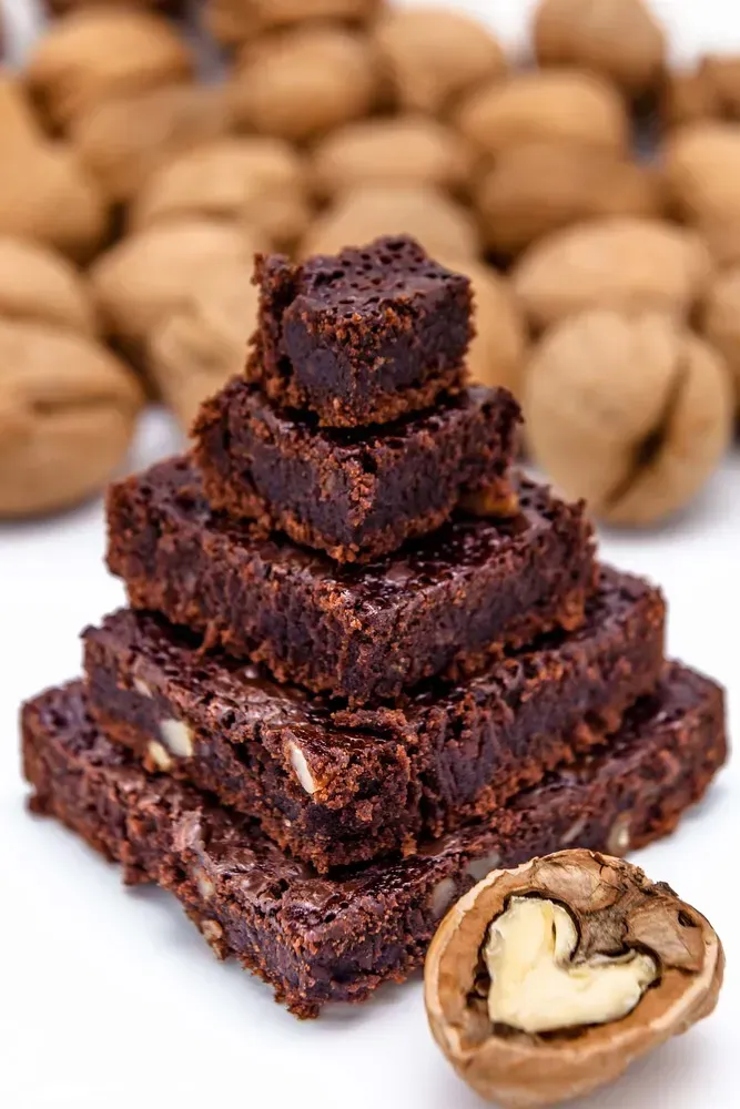 The protein brownie is presented in the shape of a stunning pyramid! Nuts are visible near the dessert.