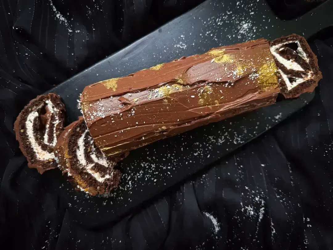 La bûche de Noël est présentée sur un plat en faïence peu profond de forme rectangulaire et de couleur bleu.