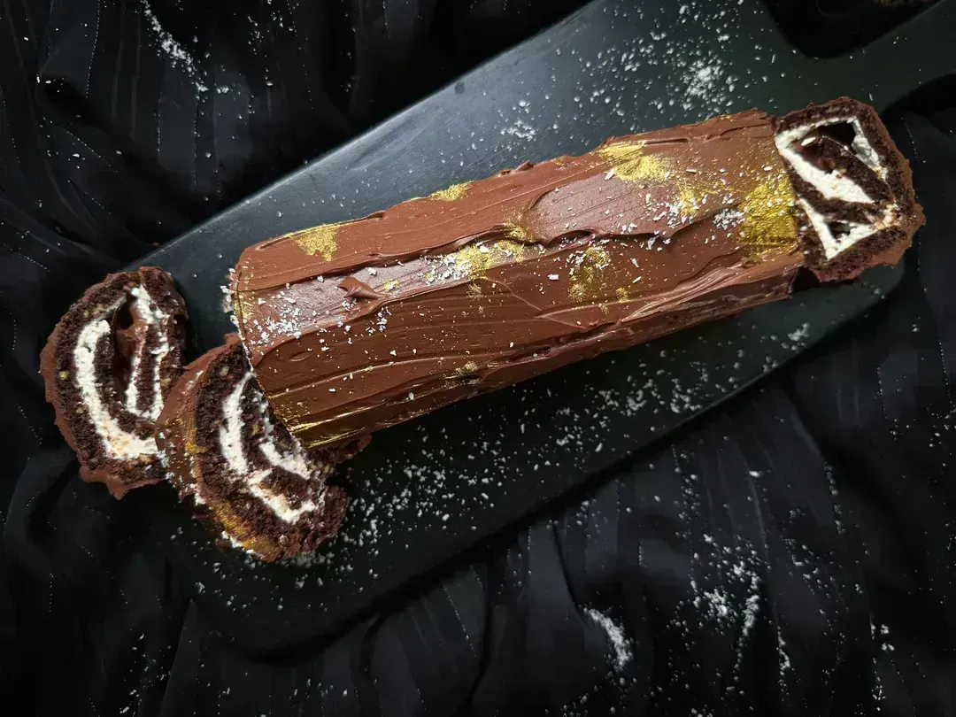 The Christmas log is presented on a shallow rectangular blue earthenware platter.