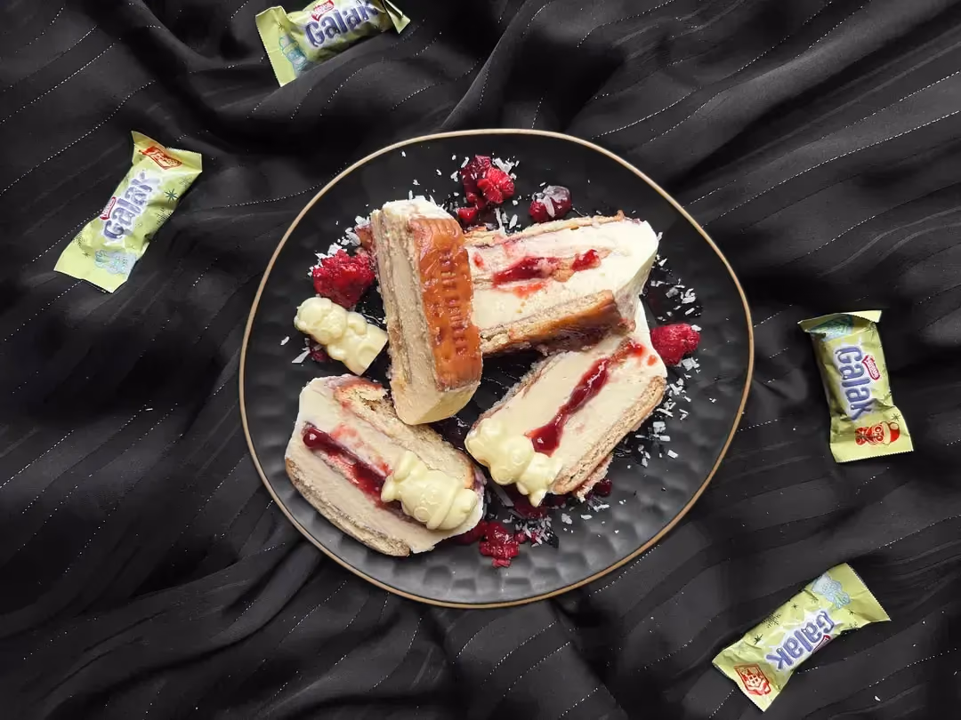 Quatre morceaux de bûche ricotta, vanille, confiture de framboise et Petit Beurre est présentée dans un plat de couleur bleu.