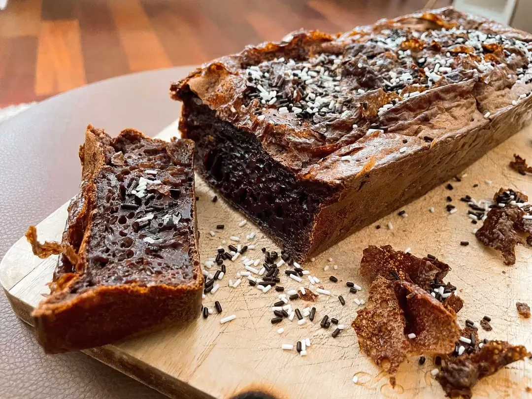 Le gâteau à la crème dessert chocolat est décoré de vermicelles au chocolat et il est posé sur une planche en bois.