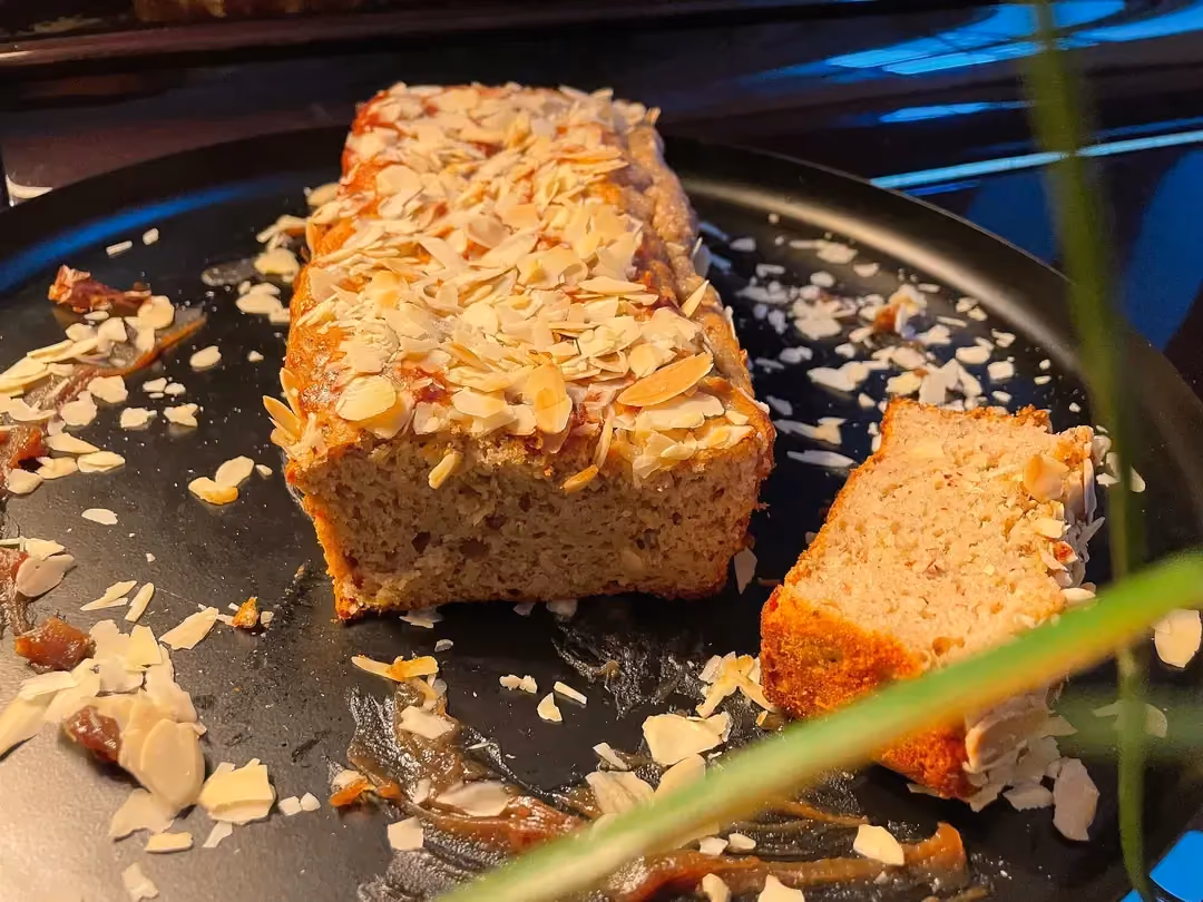 Placed on a large round platter, the chestnut cream cake is completely covered with sliced almonds. A large slice sits beside it.