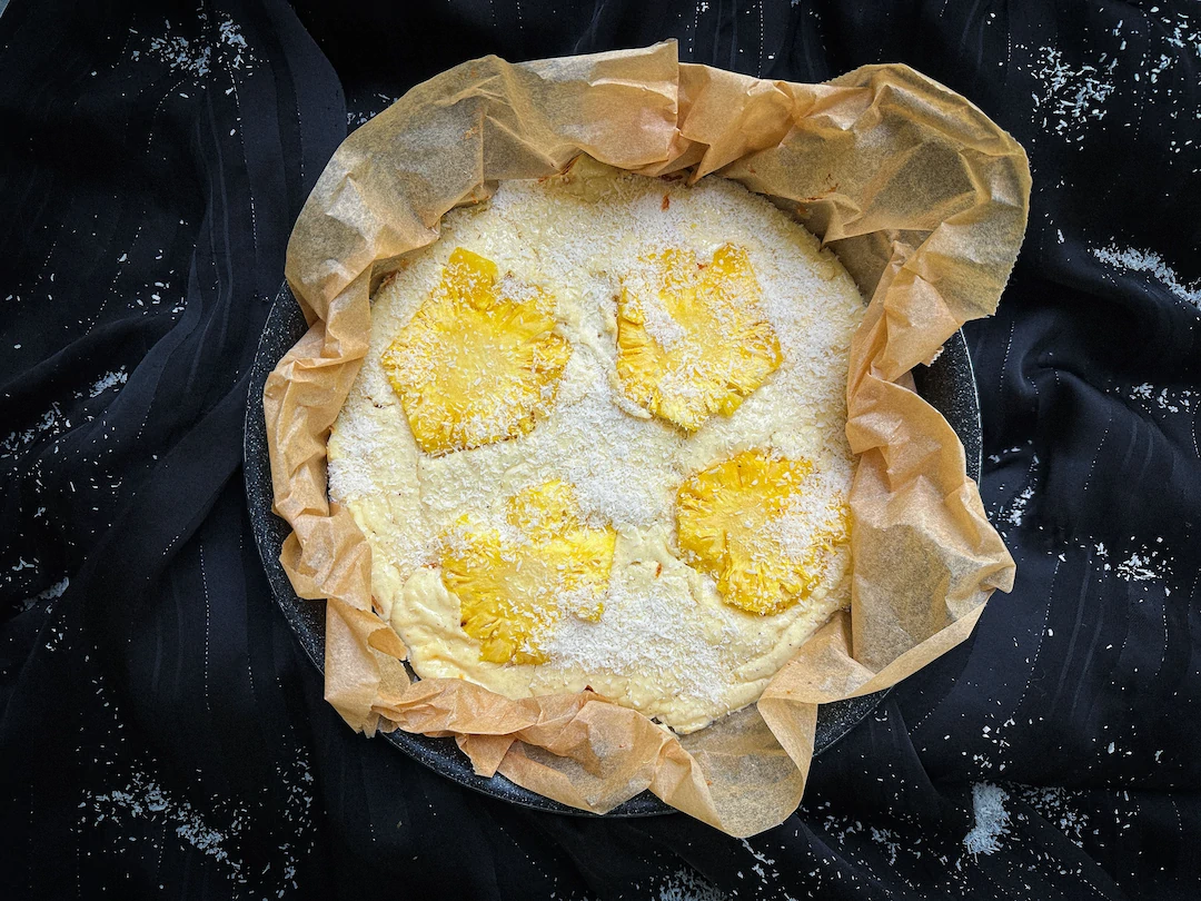 Presented in a baking pan, the cheesecake is topped with pineapple slices.