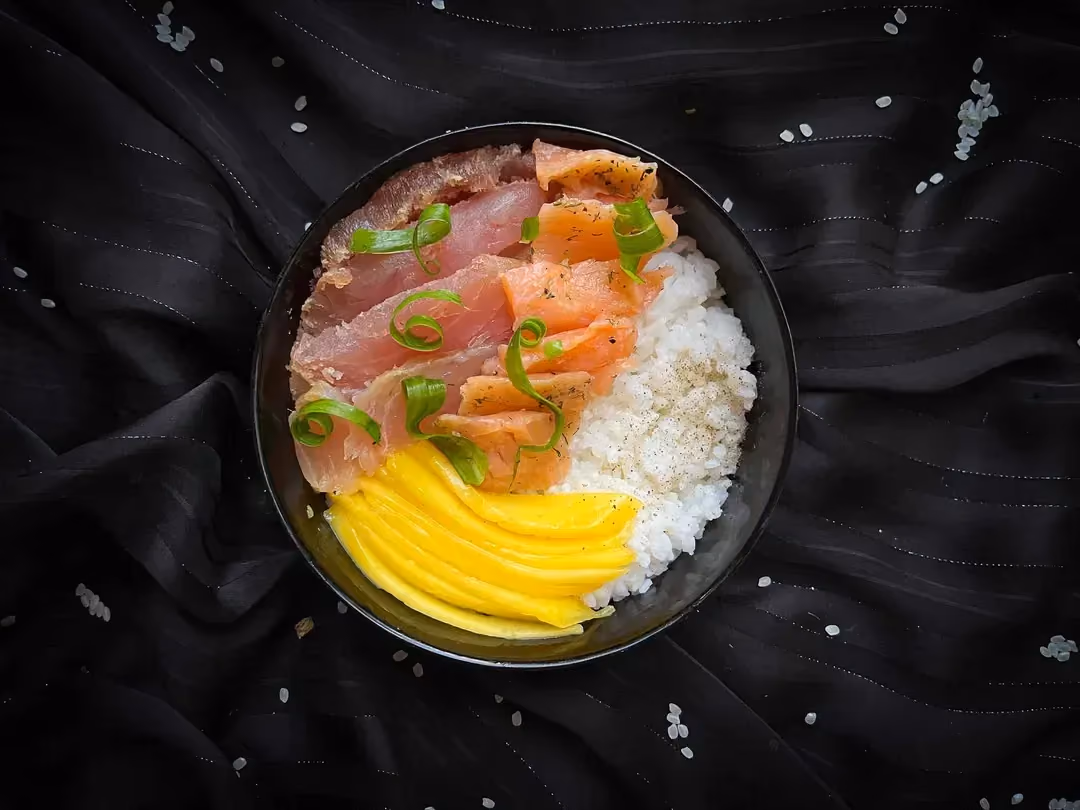 La recette de Chirashi au saumon et mangue accompagnée de riz thai est présentée dans un petit saladier.