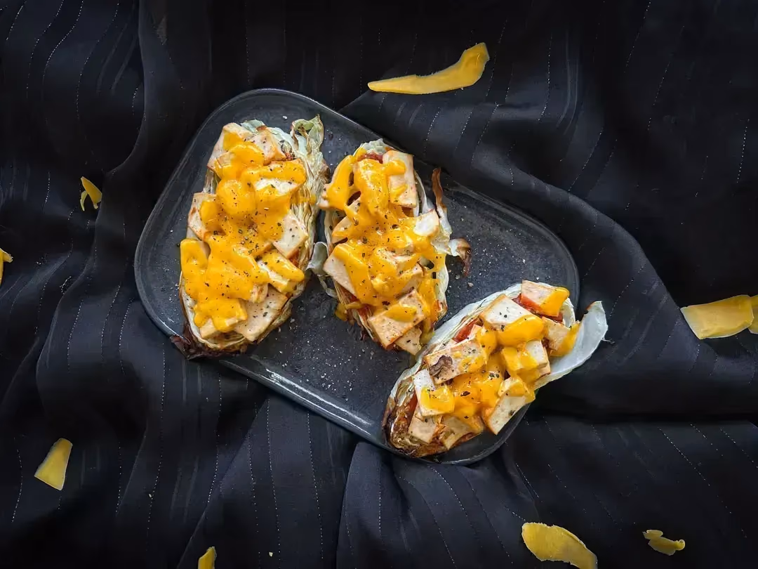 Three mini vegetarian cabbage pizzas are presented on a rectangular blue earthenware platter.
