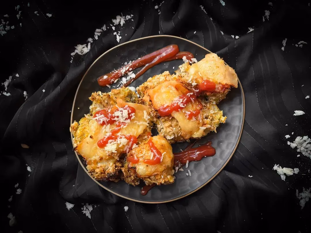 Milanese-style cauliflower is presented in a compartmentalized dish. You can see the cauliflower and turkey breast, gratinéed with cheese and ketchup.