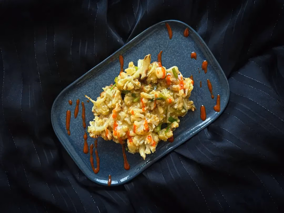 Dans un grand saladier en terre cuite se trouve les fleurons de choux-fleurs colorés par la sauce soja.