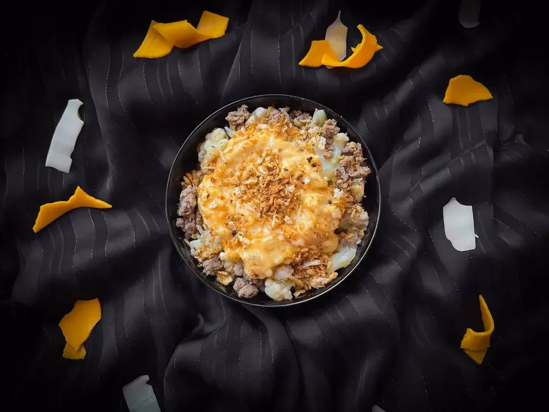 The cauliflower, ground meat, and three-cheese recipe is presented in a small blue bowl.