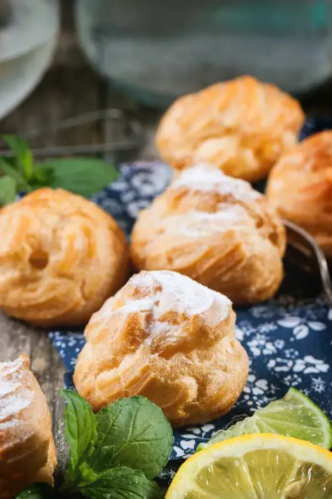 Six marlin and chili cream puffs are visible. Half a yellow lemon and a small slice are placed next to the cream puffs.