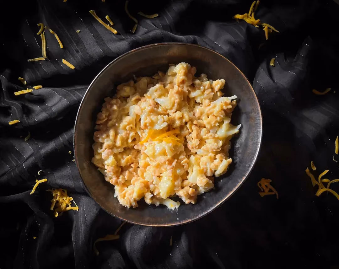 In a small bowl is a cauliflower mac-style recipe with melted grated Cheddar.