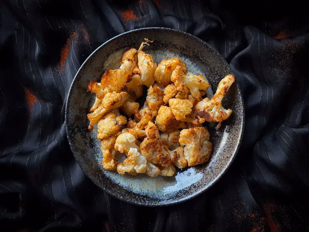 A small blue salad bowl holds our vegetarian recipe for roasted cauliflower with grated Parmesan.