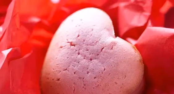 A pretty little raspberry heart is placed on a red-colored napkin.