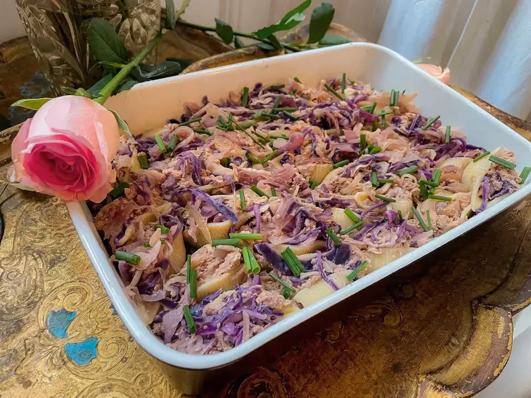 Les conchiglionis sont fourrées avec du thon et du chou rouge dans un plat à gratin. Avec en décoration des roses.