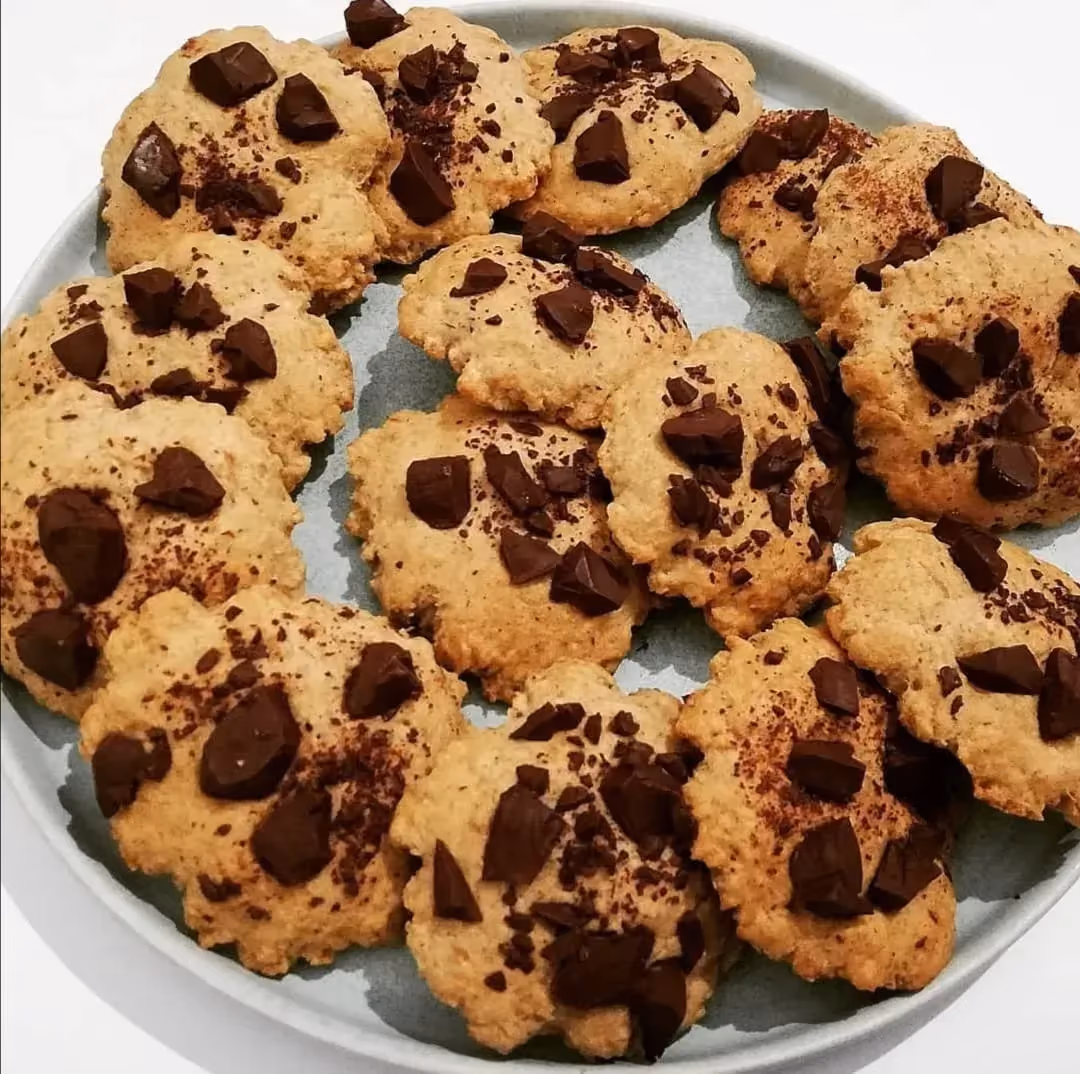 Sur une grande assiette de couleur bleue clair, quatorze cookies avec des pépites de chocolat sont prêts à être savourés.