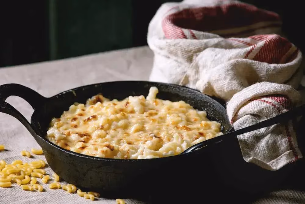 Présenté dans un gros caquelon en fonte de couleur noir, les coquillettes, blanc de dinde et fromage sont légèrement gratinées.
